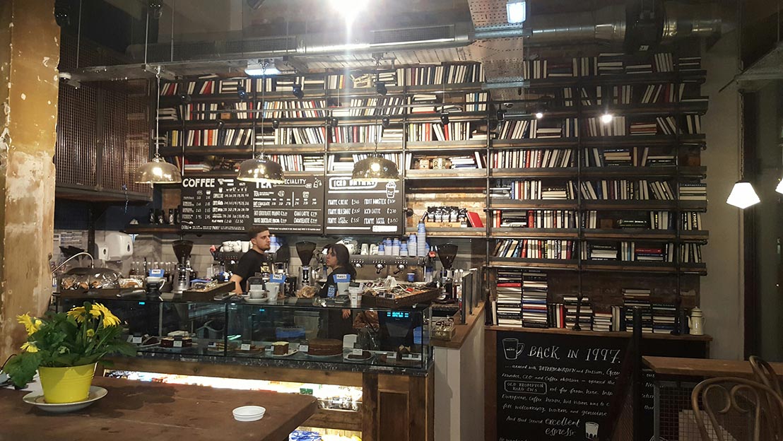 A large bookshelf behind a bar in a refurbished cafe