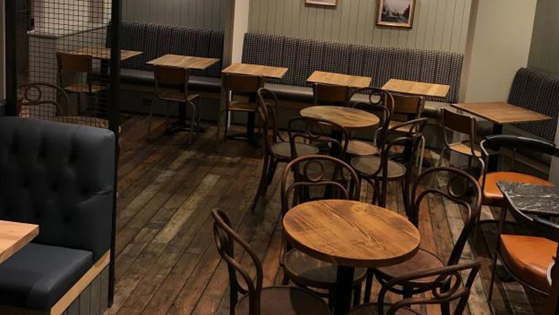 Wooden tables and chairs and sofas laid out in a refurbished cafe